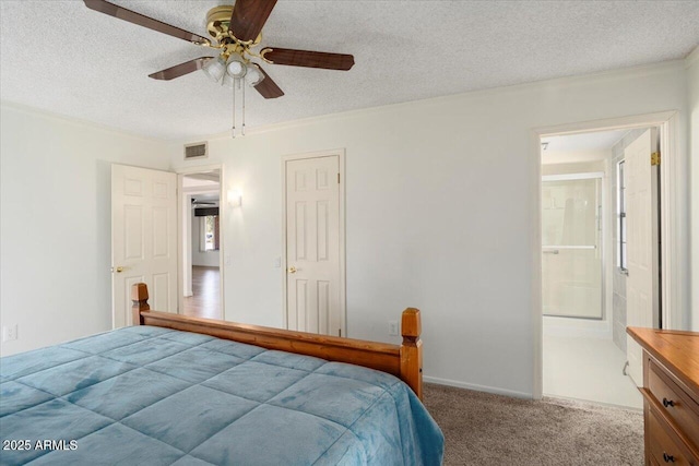 bedroom with a textured ceiling, carpet floors, ensuite bath, and ceiling fan