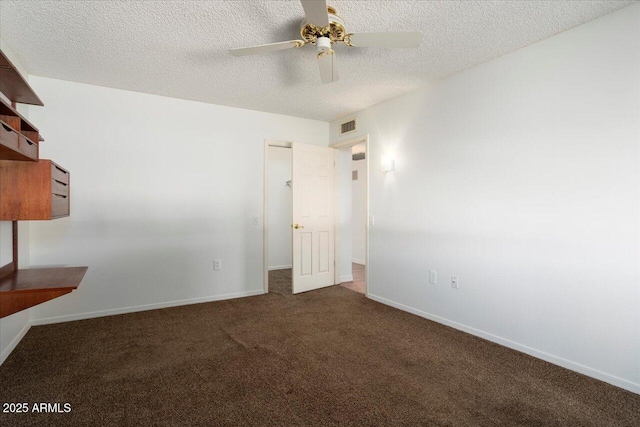 empty room with ceiling fan, dark carpet, and a textured ceiling