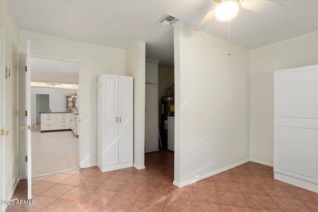 spare room with light tile patterned floors, electric water heater, and ceiling fan