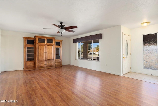 unfurnished living room with ceiling fan, a textured ceiling, and light wood-type flooring