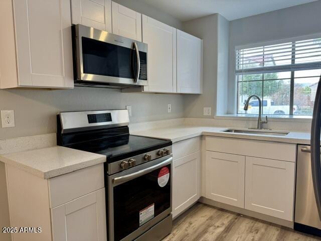 kitchen featuring white cabinetry, appliances with stainless steel finishes, sink, and light hardwood / wood-style floors