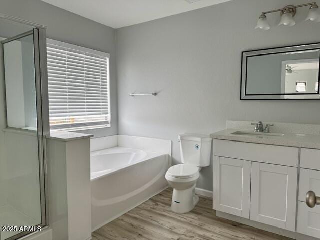 full bathroom with ceiling fan, hardwood / wood-style floors, vanity, shower with separate bathtub, and toilet