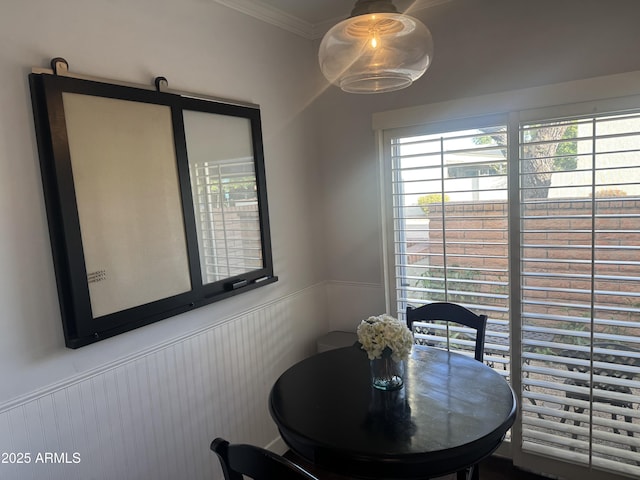 dining room with crown molding and a wainscoted wall