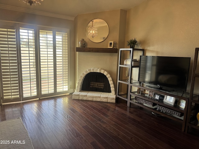 unfurnished living room with an inviting chandelier, a fireplace with raised hearth, wood finished floors, and ornamental molding