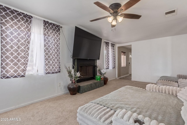 bedroom featuring baseboards, visible vents, a ceiling fan, carpet, and a fireplace