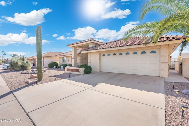 mediterranean / spanish home with an attached garage, a tiled roof, concrete driveway, and stucco siding