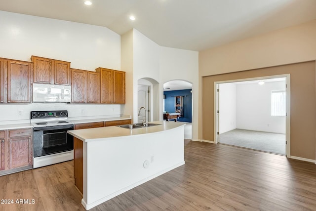 kitchen featuring white appliances, high vaulted ceiling, a center island with sink, sink, and light hardwood / wood-style floors