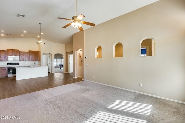 unfurnished living room featuring ceiling fan, sink, high vaulted ceiling, and dark colored carpet