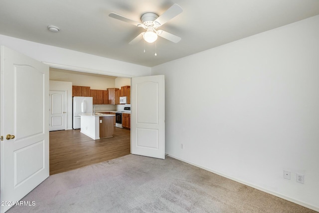 unfurnished living room featuring ceiling fan, sink, and light wood-type flooring