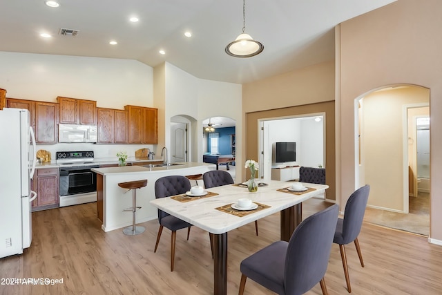 dining area with ceiling fan, sink, high vaulted ceiling, and light hardwood / wood-style flooring