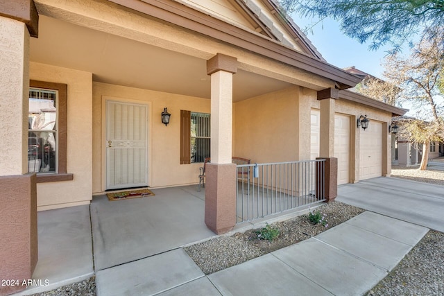 view of exterior entry featuring a garage and covered porch