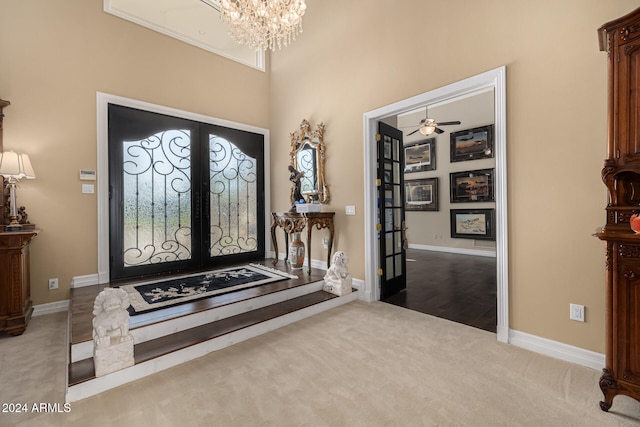 carpeted entryway featuring french doors and ceiling fan with notable chandelier