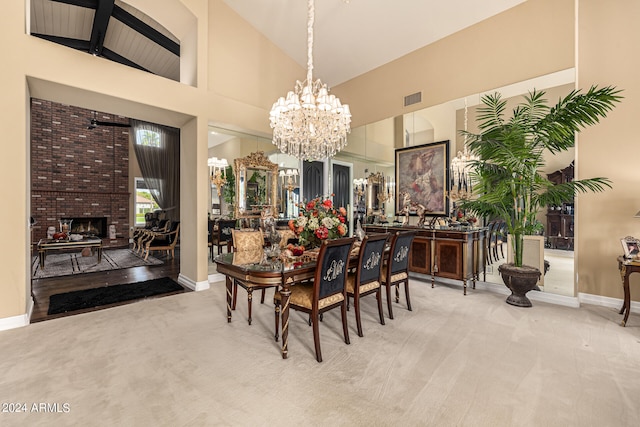 dining space featuring carpet floors, a fireplace, a chandelier, and high vaulted ceiling