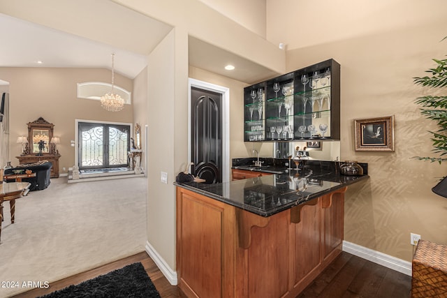 bar featuring decorative light fixtures, a chandelier, dark hardwood / wood-style floors, dark stone countertops, and vaulted ceiling