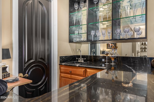 bar featuring dark stone countertops and sink