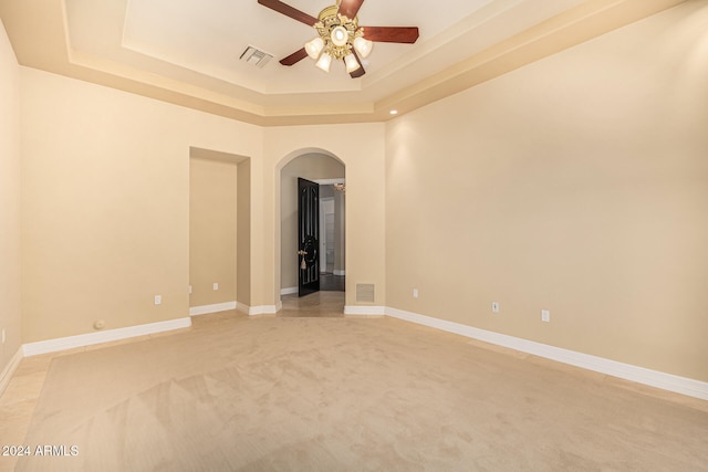 carpeted spare room featuring ceiling fan and a tray ceiling