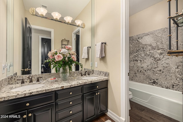 full bathroom with wood-type flooring, vanity, bathtub / shower combination, and toilet