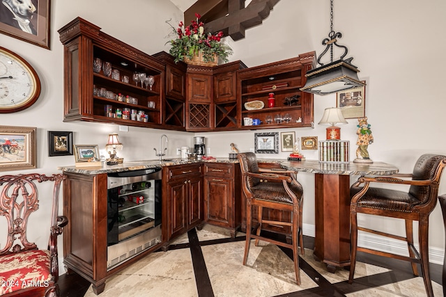 bar with hanging light fixtures, stone counters, wine cooler, and sink