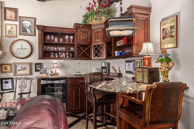 bar with stone countertops, beverage cooler, and sink