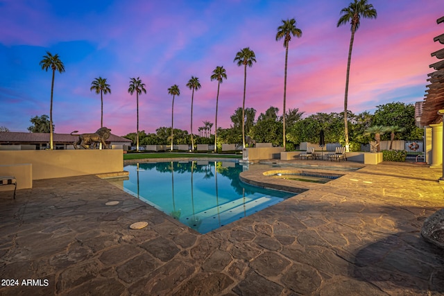 pool at dusk featuring a patio area