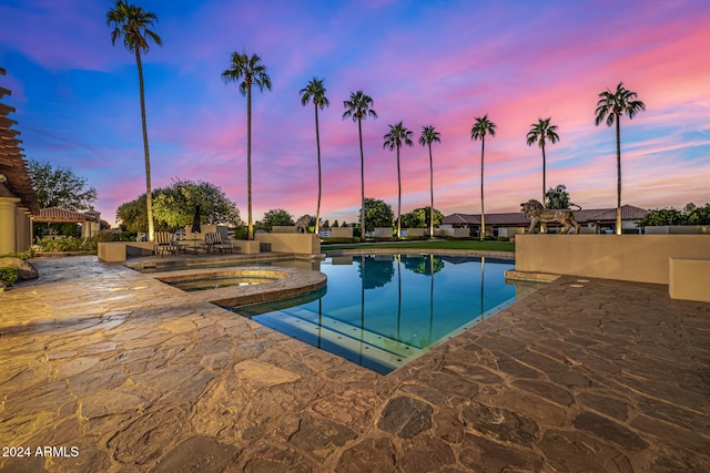 pool at dusk with a patio area