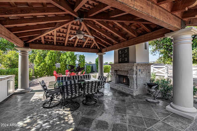 view of patio featuring ceiling fan, a gazebo, and an outdoor stone fireplace