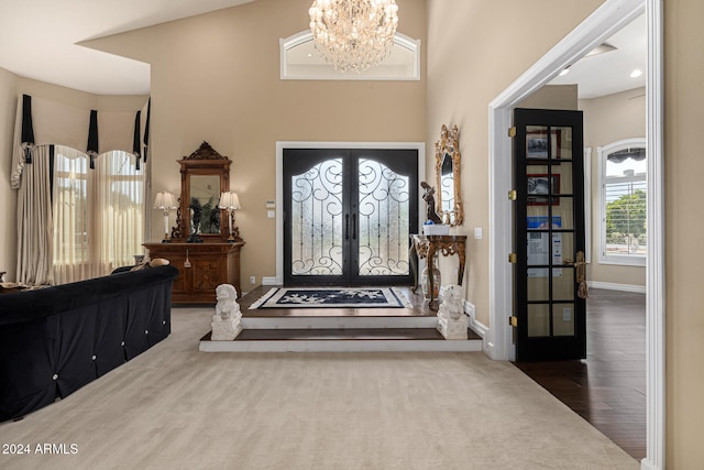 entryway featuring a towering ceiling, a notable chandelier, french doors, and dark hardwood / wood-style flooring