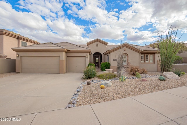 mediterranean / spanish home featuring concrete driveway, a tiled roof, a garage, and stucco siding