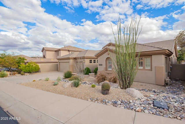 view of front of property with concrete driveway, a tiled roof, a garage, and stucco siding