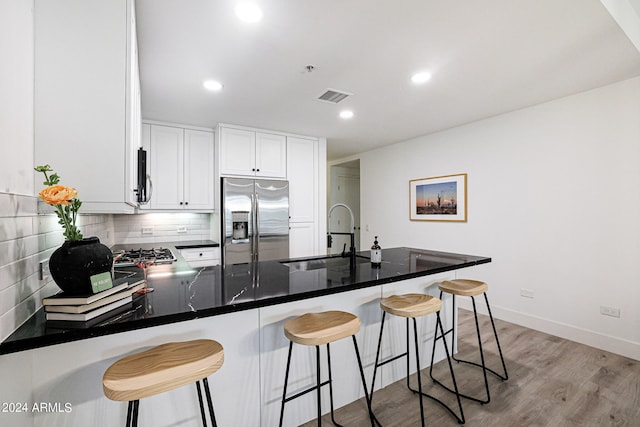 kitchen featuring light hardwood / wood-style floors, a kitchen bar, stainless steel appliances, backsplash, and sink