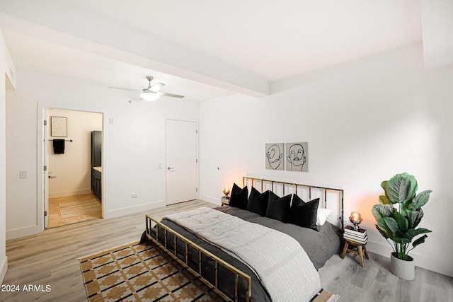 bedroom featuring ceiling fan, light hardwood / wood-style flooring, connected bathroom, and beam ceiling