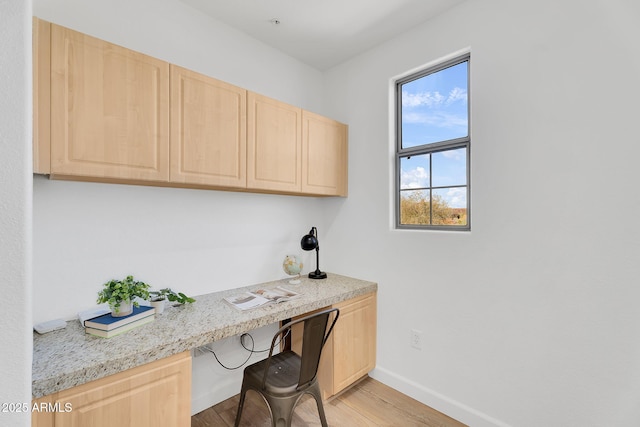 office space featuring built in study area, light wood-style floors, and baseboards