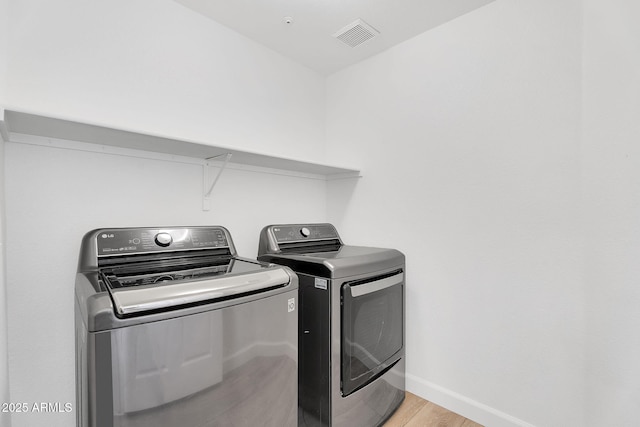 washroom with separate washer and dryer, light wood-type flooring, and baseboards