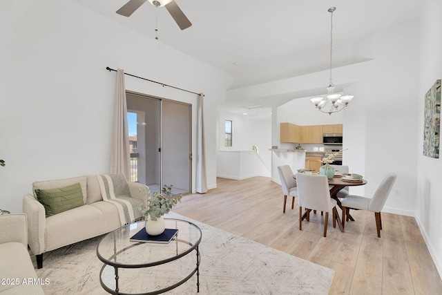 living room featuring light wood-type flooring, a chandelier, a ceiling fan, and baseboards