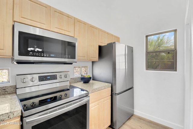 kitchen featuring appliances with stainless steel finishes, light brown cabinetry, light countertops, and light wood-style flooring