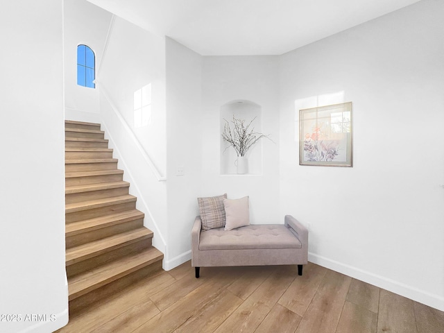 sitting room featuring stairway, hardwood / wood-style flooring, and baseboards