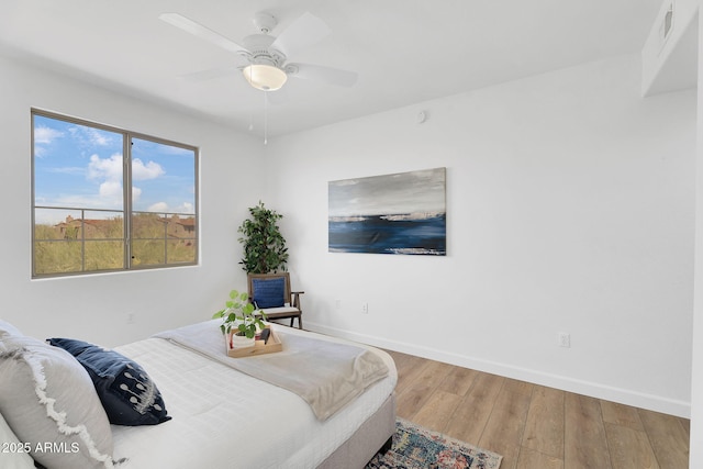 bedroom featuring baseboards, wood finished floors, and ceiling fan