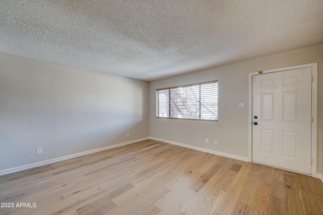 empty room featuring a textured ceiling and light hardwood / wood-style flooring