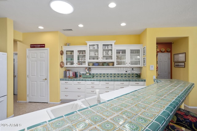 19714 N Concord Dr, Surprise, AZ 85374 - kitchen with tile counters, white cabinets, baseboards, glass insert cabinets, and recessed lighting