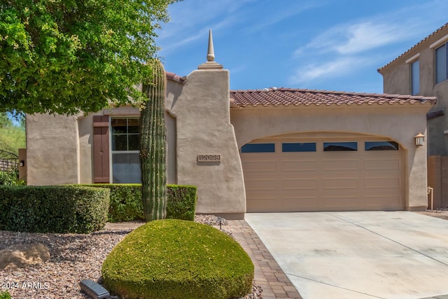 view of front of home with a garage, driveway, a tiled roof, and stucco siding