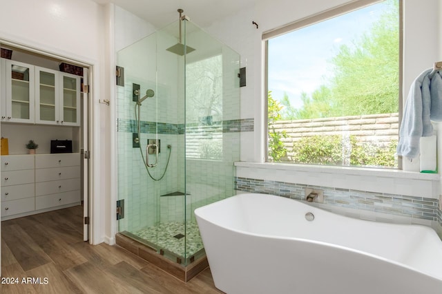 full bath featuring a freestanding tub, plenty of natural light, a shower stall, and wood finished floors