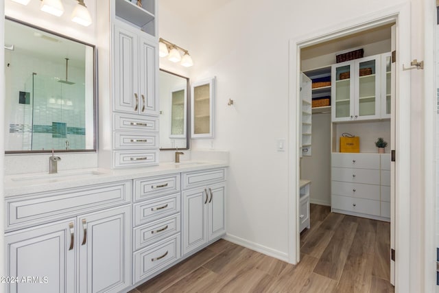 full bathroom with a stall shower, a sink, and wood finished floors