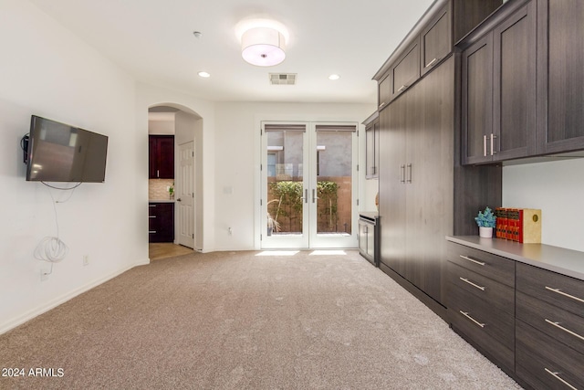 interior space with visible vents, arched walkways, light colored carpet, dark brown cabinets, and backsplash