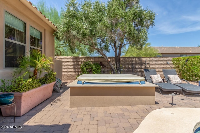 view of patio / terrace featuring a jacuzzi and fence