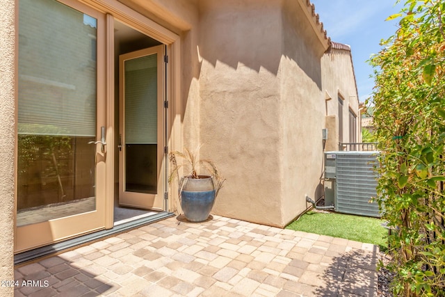 doorway to property with central air condition unit, a patio area, and stucco siding