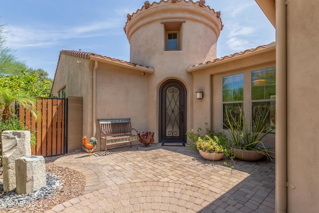 doorway to property featuring a tiled roof, a gate, and stucco siding