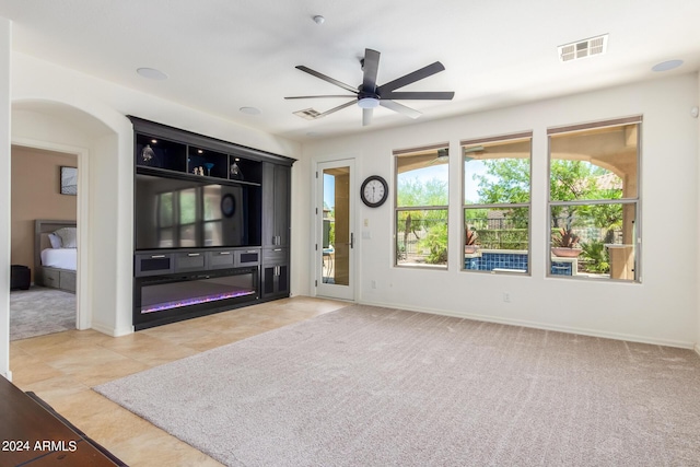 living room with ceiling fan, visible vents, and light colored carpet