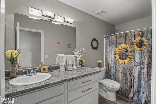 bathroom featuring walk in shower, wood-type flooring, a textured ceiling, toilet, and vanity