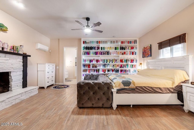 bedroom featuring ceiling fan, light wood-type flooring, an AC wall unit, and connected bathroom