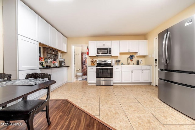 kitchen with white cabinets, light tile patterned flooring, sink, and appliances with stainless steel finishes